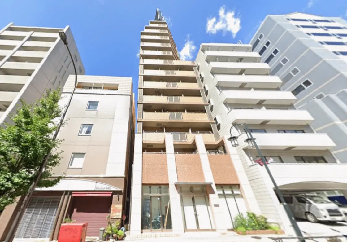 - 高層ビルと隣接する住宅街の風景、青空を背景にしたモダンな外観の建物