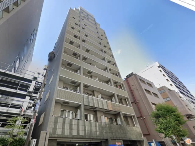- 近代的な外観のマンションビル、空が青く広がる中、隣接する建物とのコントラストが際立つ風景