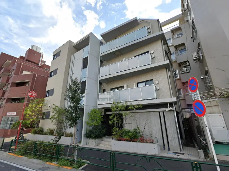 - モダンな外観のアパートメントビル、隣接する建物と植栽が調和した街並みの風景