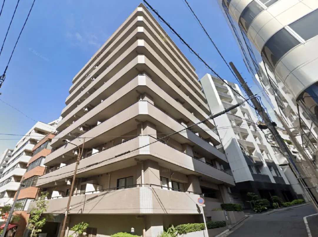 - 都市の集合住宅、モダンな外観の高層ビル、明るい青空と周囲の街並みが映える風景