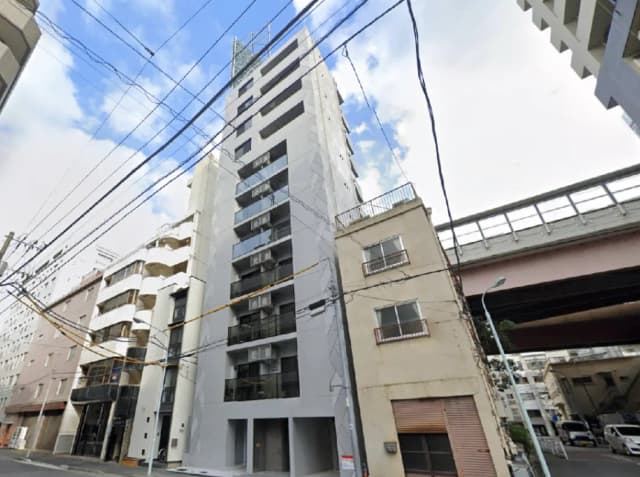 - モダンなデザインの高層マンションと隣接する古い建物、青空に映える外観と電線のある街並み