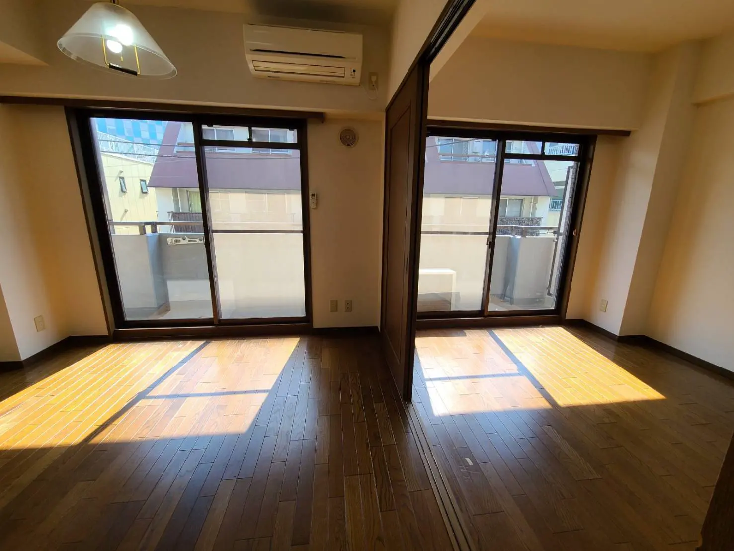 日当たりが良い広々とした部屋、木製フローリングと大きな掃き出し窓、バルコニー付きのインテリア
