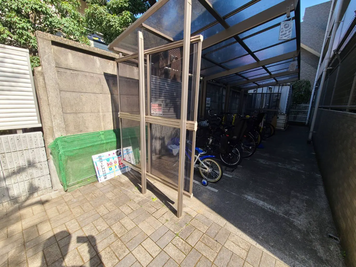 日本のマンションの駐輪場、屋根付きで自転車が並んでおり、午後の日差しの下にある都市の屋外スペース