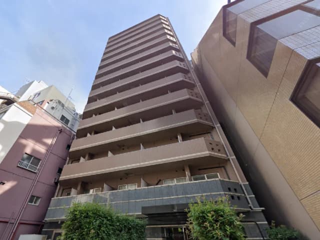 - 都市部の近代的な高層マンション、バルコニーが付いた外観、隣接するビルと緑の植栽が見える景観