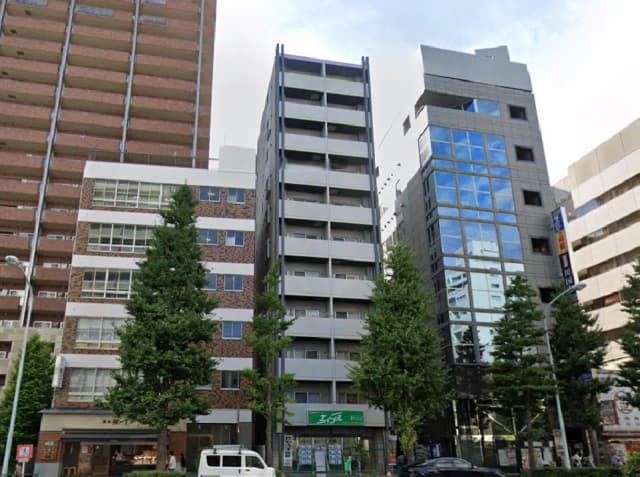 - 都市部に立地するモダンなビル群、周囲には緑の木々と商業施設が併設される風景