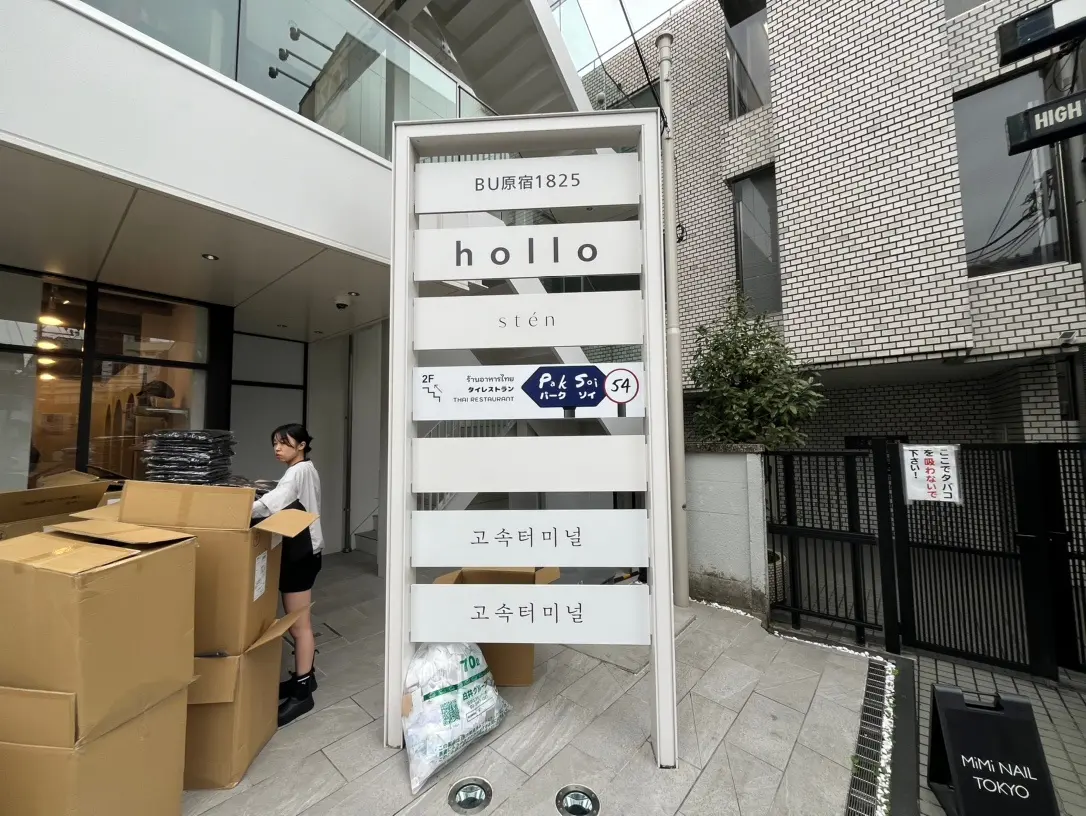 ダンボール箱が積まれた都市のビル入り口、看板に複数の店舗名が記載