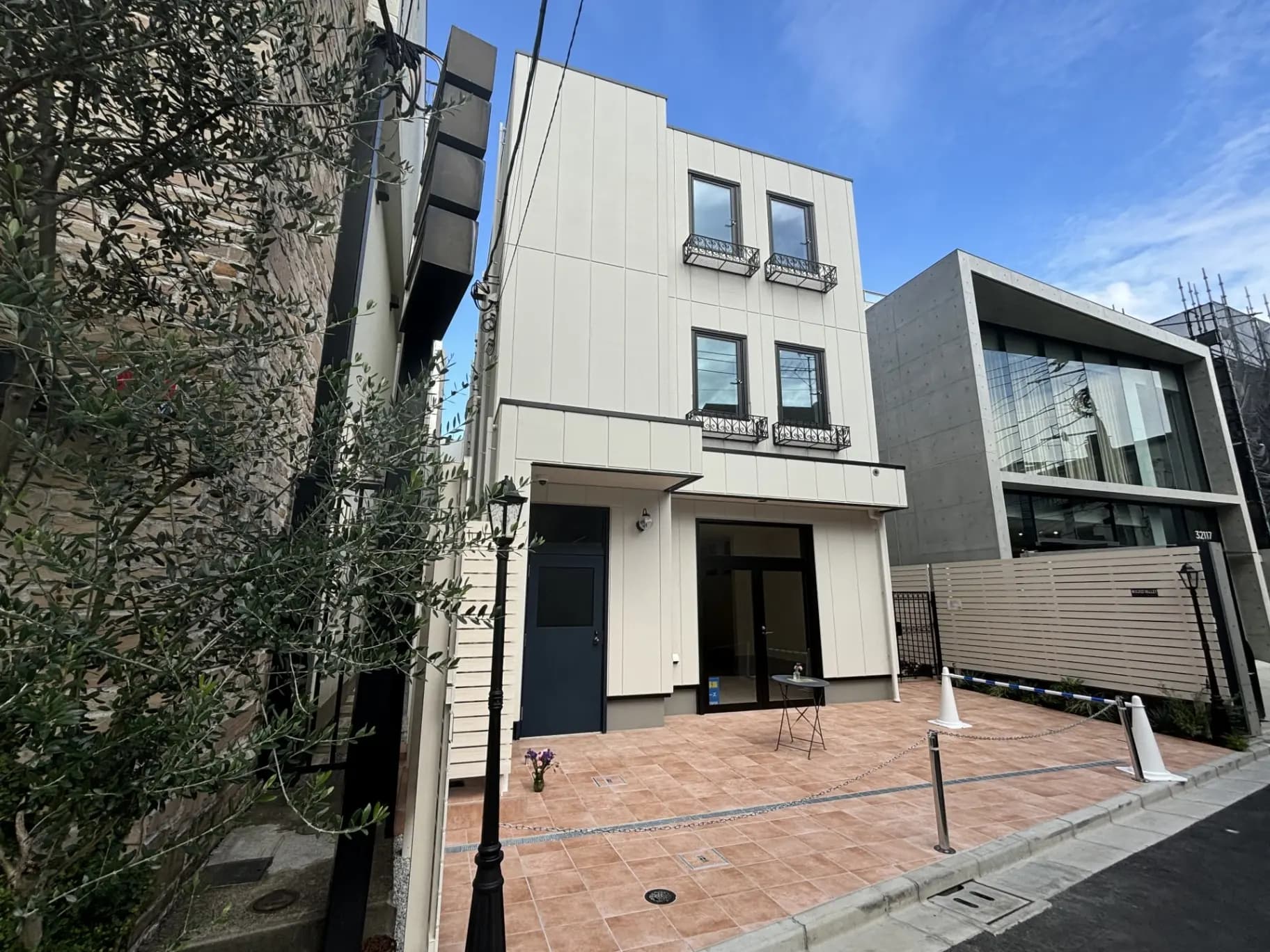 現代的な外観の都市型住宅、オリーブの木がある前庭、クリーム色のファサードとバルコニー