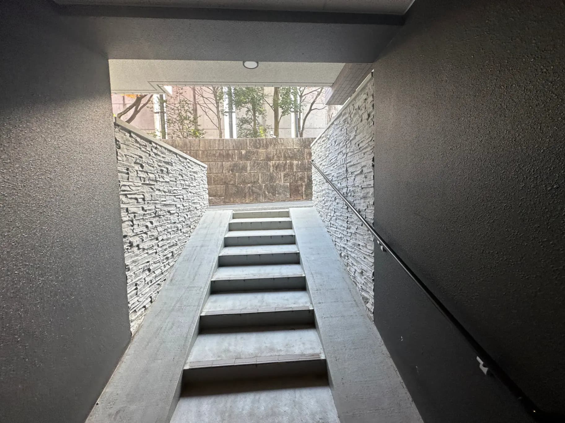 モダンな建築様式の階段、石の壁とコンクリートの踏面、自然光が差し込む明るい空間