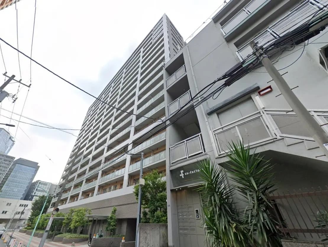 現代的なマンションの外観、都市環境に位置し、植栽が施された歩道
