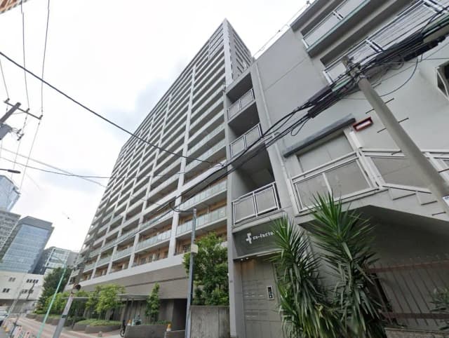 現代的なマンションの外観、都市環境に位置し、植栽が施された歩道