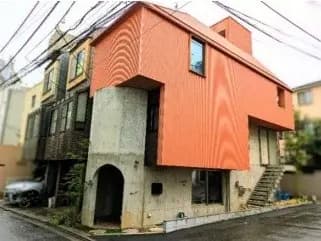 都市風景に溶け込む個性的なデザインのオレンジ色の外壁を持つ現代的な住宅