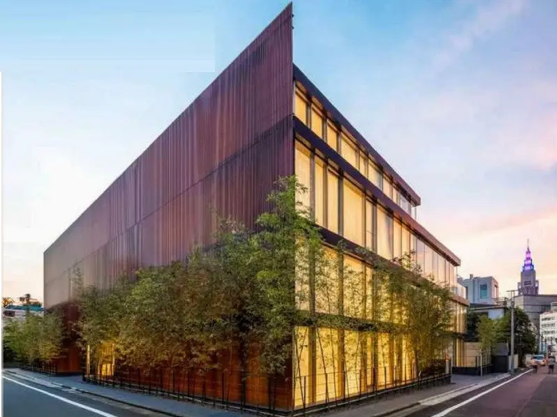 現代的な建築スタイルのオフィスビル、暖色系の照明とガラス張りのファサード、緑化された周辺환경