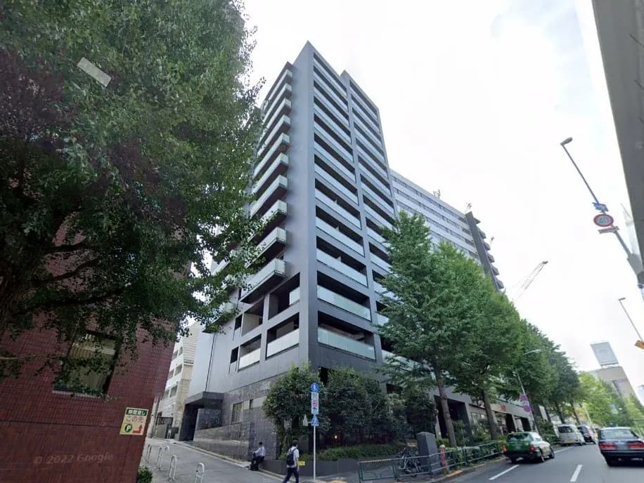 都市の景観に溶け込む現代的なマンション、歩行者と交通、緑豊かな街路樹