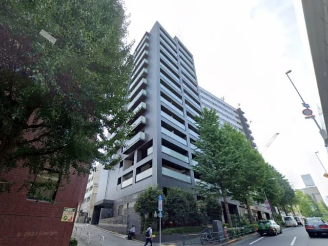 都市の景観に溶け込む現代的なマンション、歩行者と交通、緑豊かな街路樹