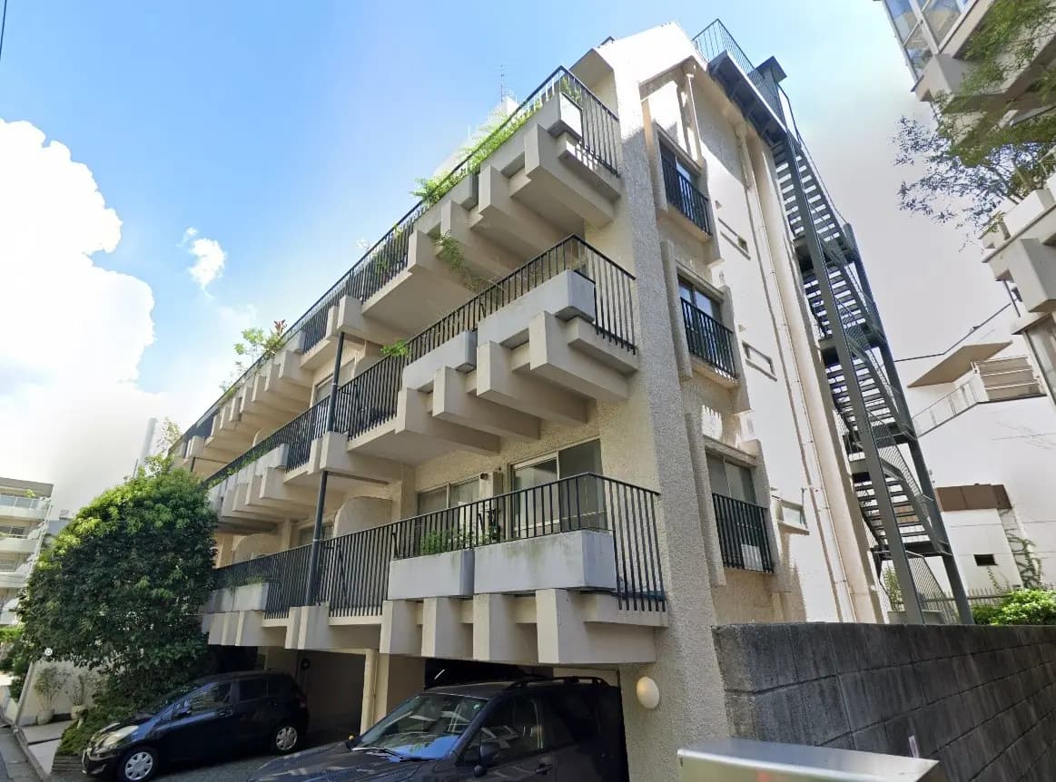マンションの外観と駐車場、緑豊かなベランダと外階段がある都市型住宅