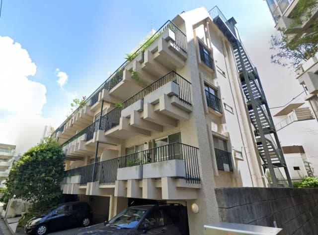 マンションの外観と駐車場、緑豊かなベランダと外階段がある都市型住宅