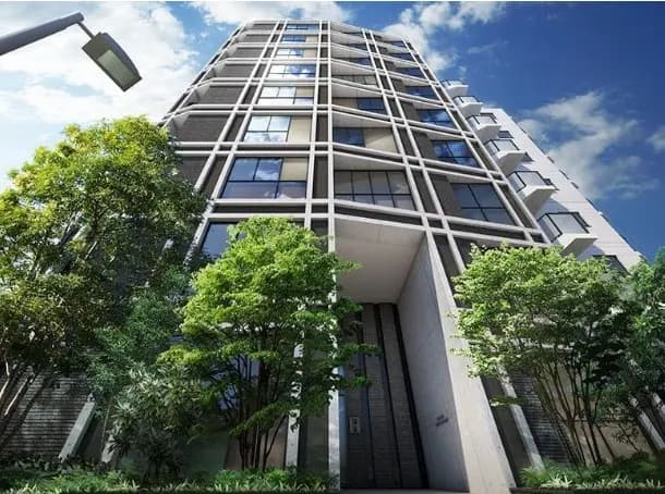 新築のモダンなデザインのマンション外観、緑豊かな樹木とクリアな青空