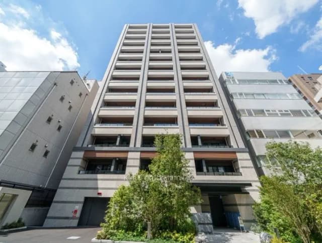 快適な都市生活を支えるモダンなマンションの外観、晴れた日の青空と緑の植栽