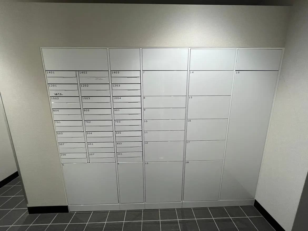 - 郵便ポストが並ぶ建物内の共用スペース、整然としたデザインで番号が記載された無地のボックス