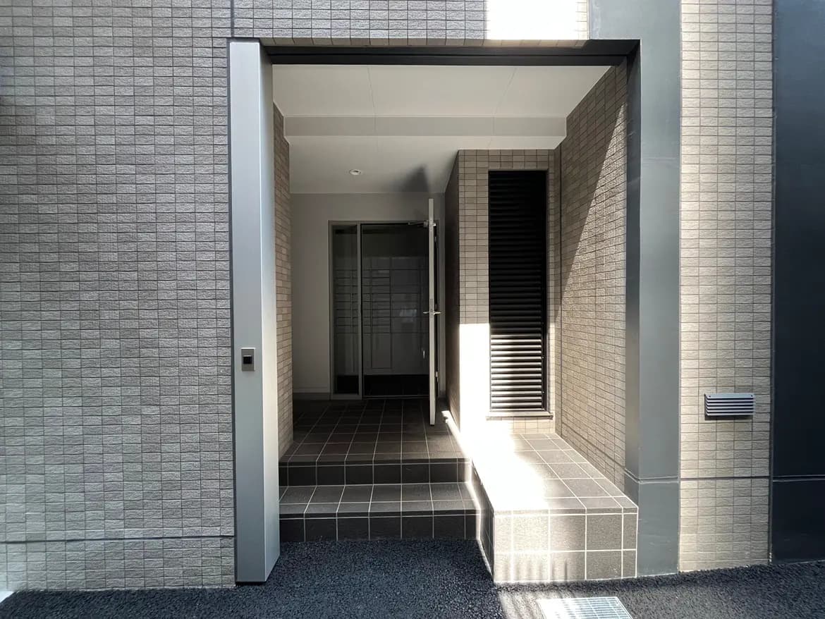 - 現代的なデザインのエントランス、タイル張りのステップと明るい光が差し込む居住空間の入り口