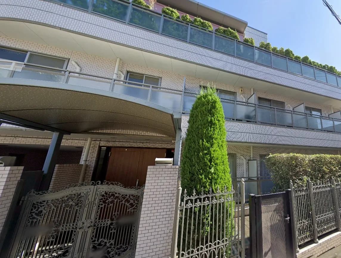 現代的なマンションの外観、白いタイル壁、ガーデニング付きのバルコニー、鉄製の門扉