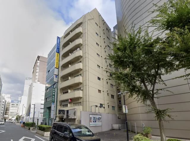 日本の都市の住宅街にあるマンションと周辺の通り、駐車中の自動車と新緑の樹木