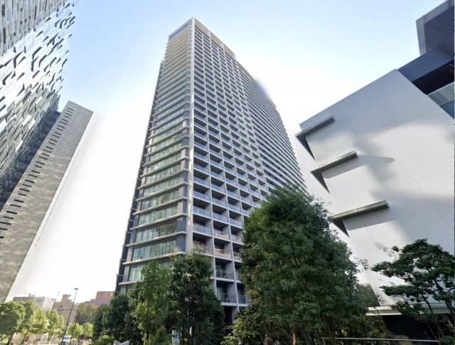現代的な高層マンションと近代的な建築が混在する都市風景、青空と緑豊かな樹木