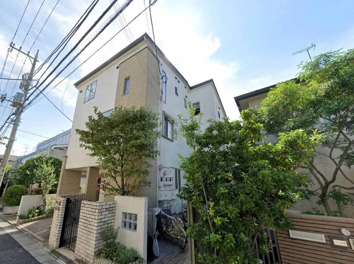 都市の閑静な住宅街にある現代的なデザインの家、青空の下で木々に囲まれた景色