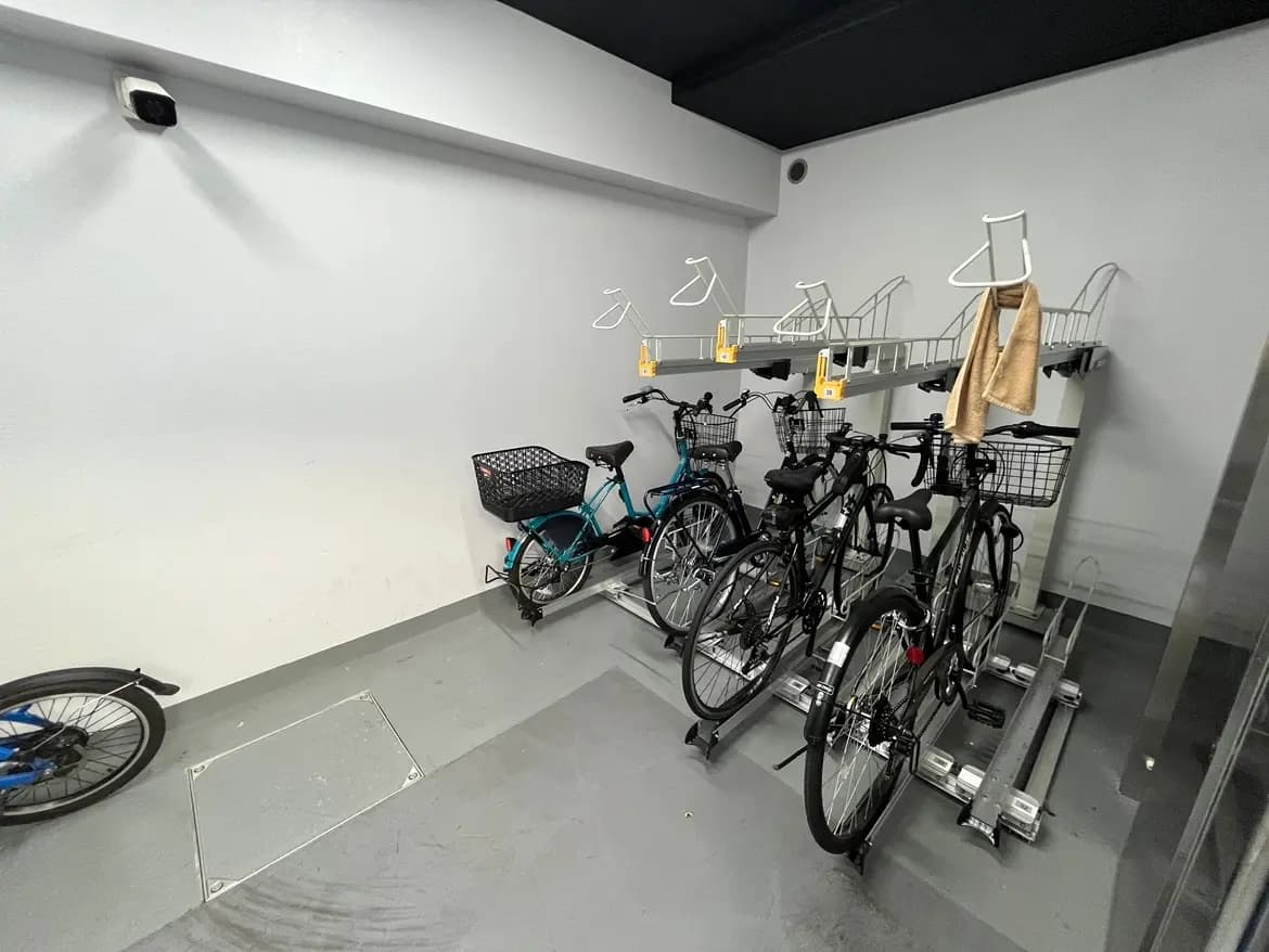 きれいに整理された自転車駐輪スペース、壁掛けの自転車ラック、白い壁に黒い床のシンプルなデザイン