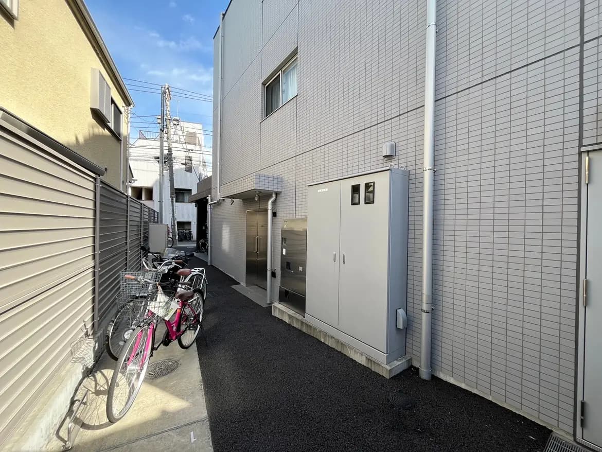 都市の住宅街にある狭い道、駐輪された自転車、明るい午後の日差し