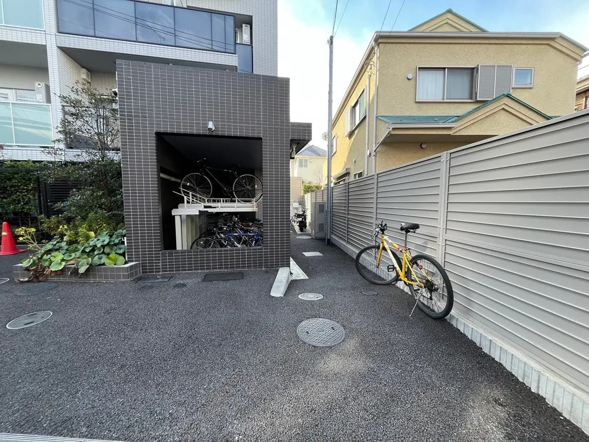 都会的な住宅街にある自転車置き場とモダンな建物、緑植物が美しい外観デザイン