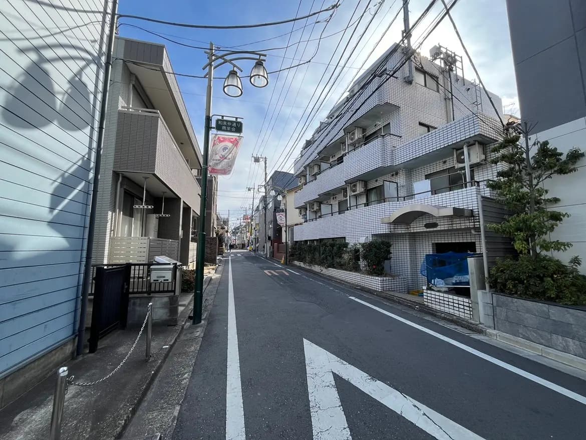 日本の都市部の狭い通り、アパート、街灯、そして日中の明るい空