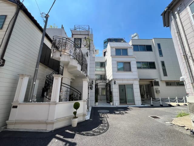 - 美しい白壁の住宅、回廊とアイアンバルコニーを備えたエントランス、晴れた青空の下に広がる現代的な外観