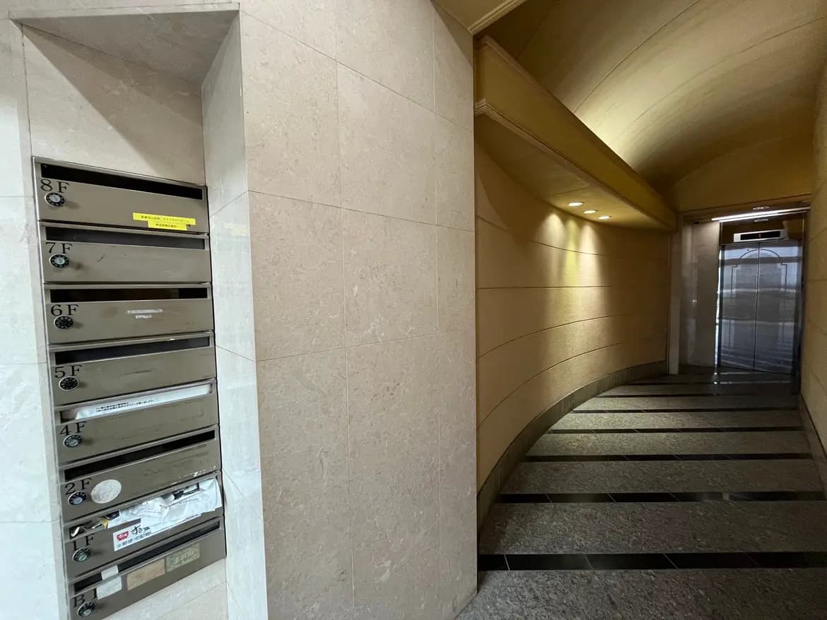 マンションのエントランスホール、タイル貼りの床、壁に取り付けられた郵便受け, 照明のある廊下