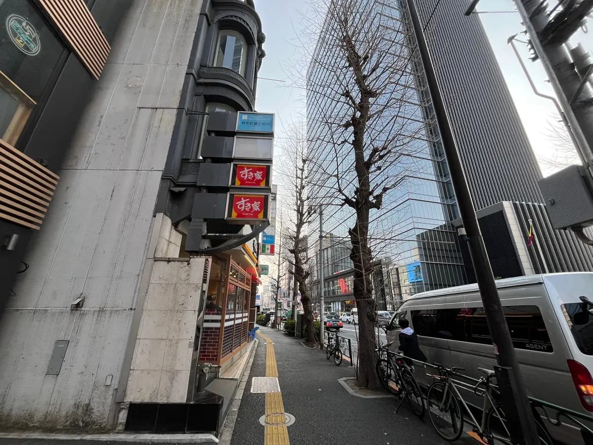 都心の繁華街にある狭い歩道と自転車、通り沿いの商店と高層ビル、現代的な都市の風景
