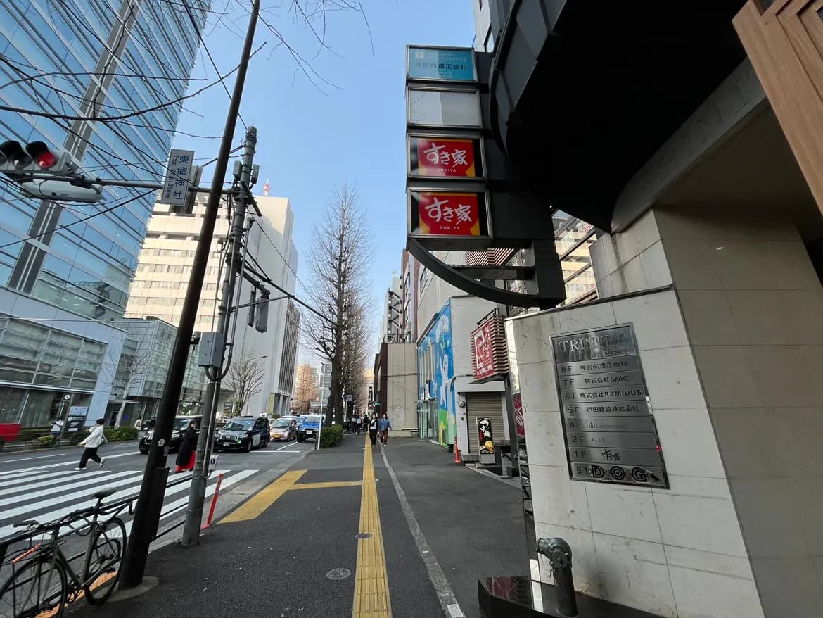 都会の通り角にある看板、晴れた日の歩行者と自転車、交通信号と建物のファサード