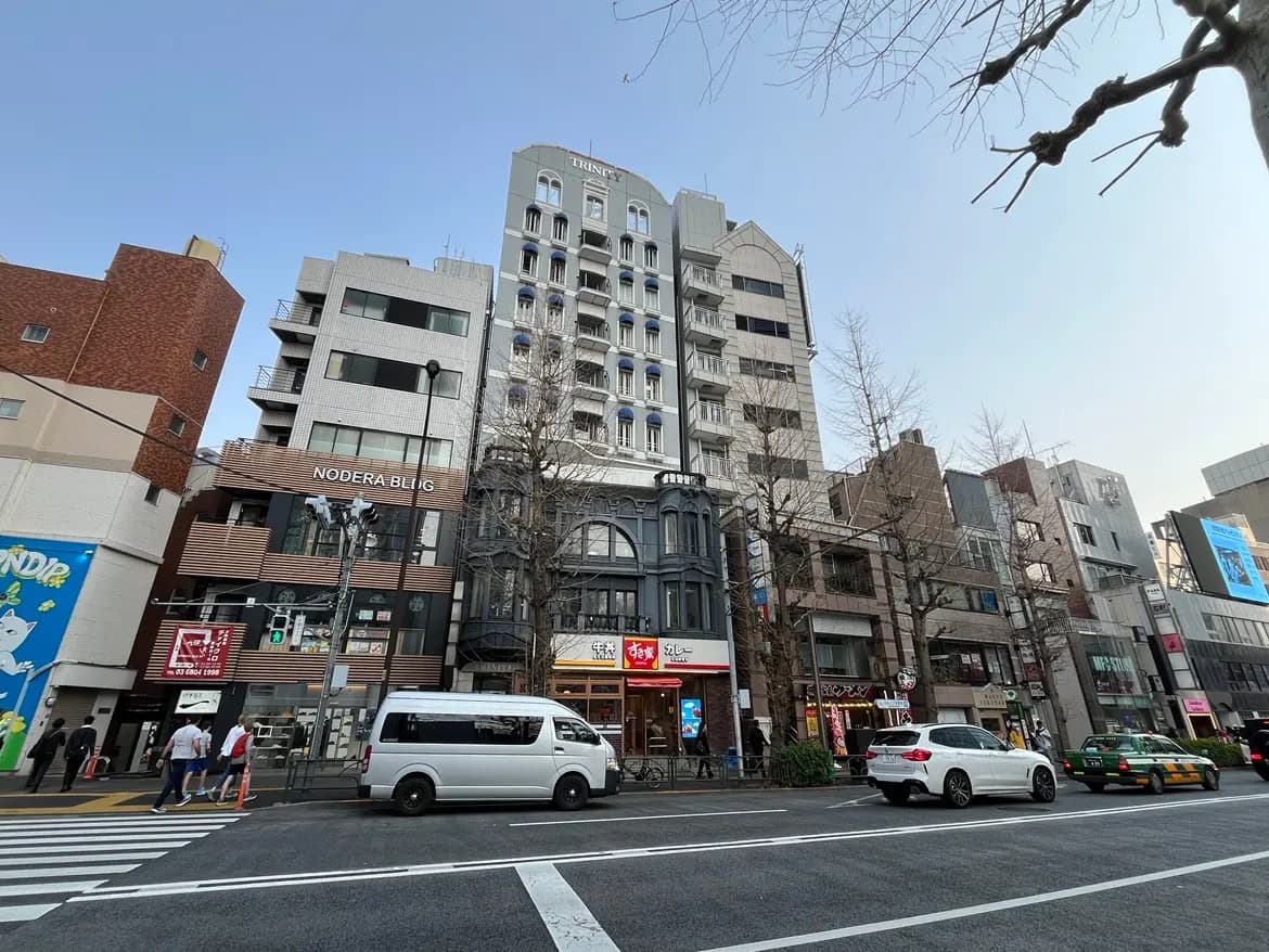 都市の通り景色、様々な建築様式のビルと店舗、歩行者と通行中の車