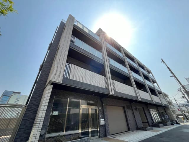 都市の近代的なアパートメントビル、ブラックタイル張りの外壁とバルコニー、晴れた日の太陽光が輝く