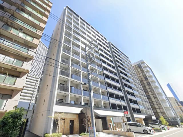 - 近代的な外観のマンションビル、隣接する建物とのコントラスト、晴れた青空の下に立つ様子