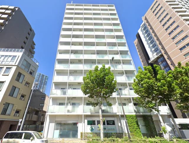 - モダンな外観の高層マンション、ガラスバルコニーと緑豊かな植栽が特徴的な都市部の風景