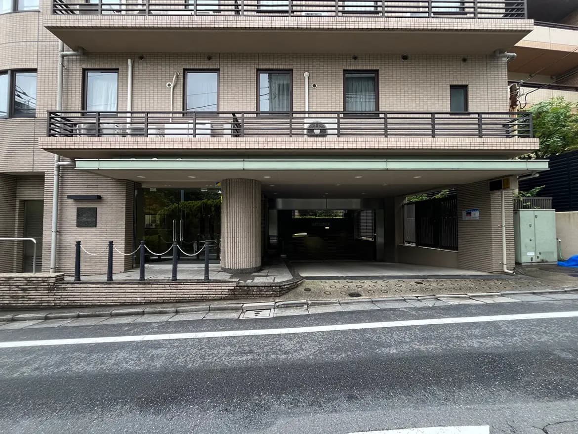 - モダンなデザインのマンションのエントランス、ガラス扉と柱、周囲にチェーンフェンスがある外観
