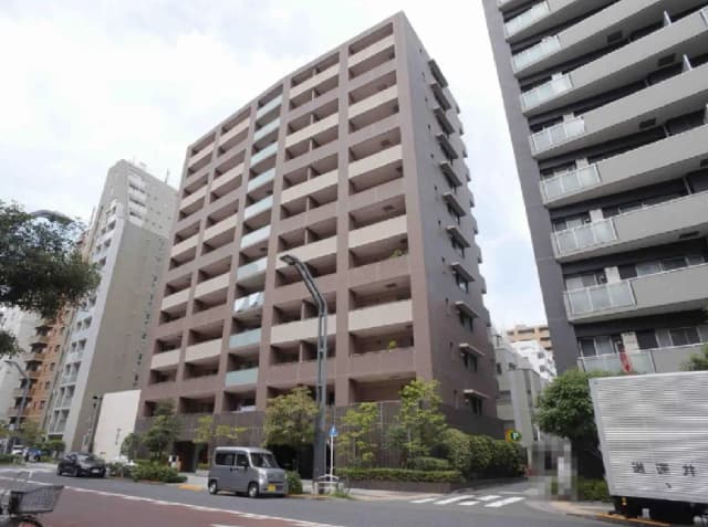 - モダンなデザインのマンション外観、周囲に緑の植栽があり、交通の便利な都市環境に位置している様子