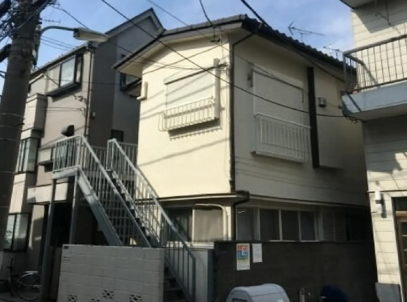 - 階段付きのアパートメント、明るい外壁と窓、周囲の電線が見える都市の風景