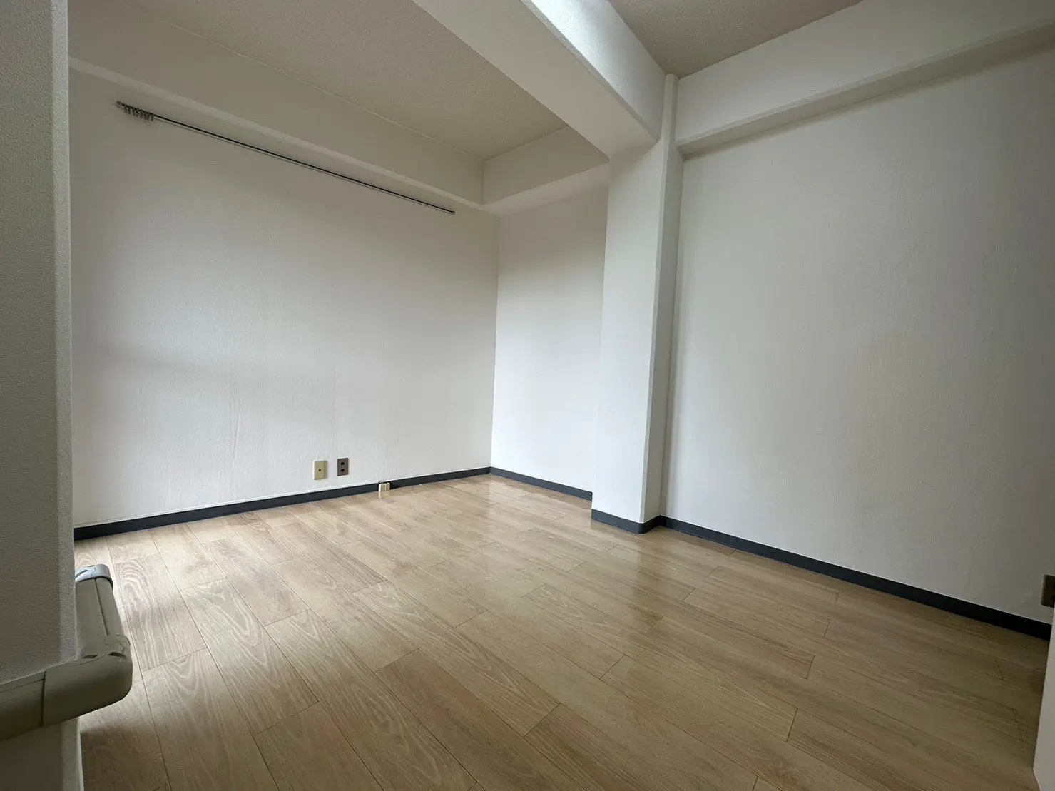 明るく広々とした空の部屋、木目のフローリング、白い壁面、シンプルなインテリアデザイン
