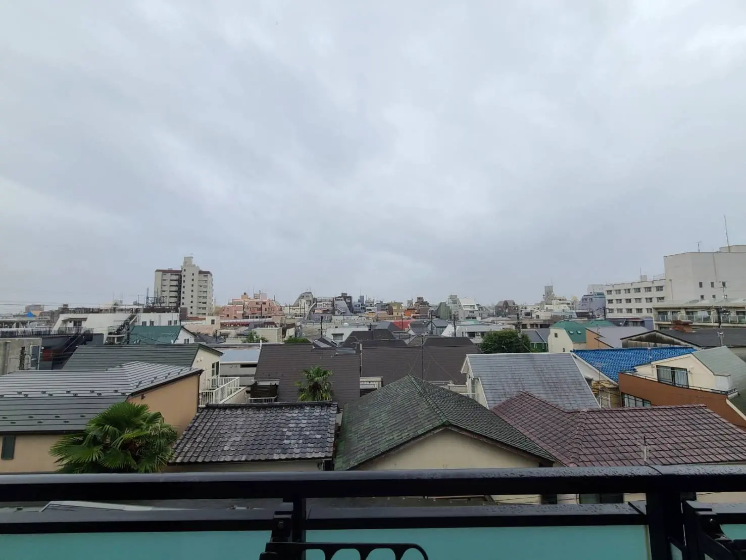 雲がかかった空の下、日本の住宅街を見渡す風景、屋根や建物のまちなみ