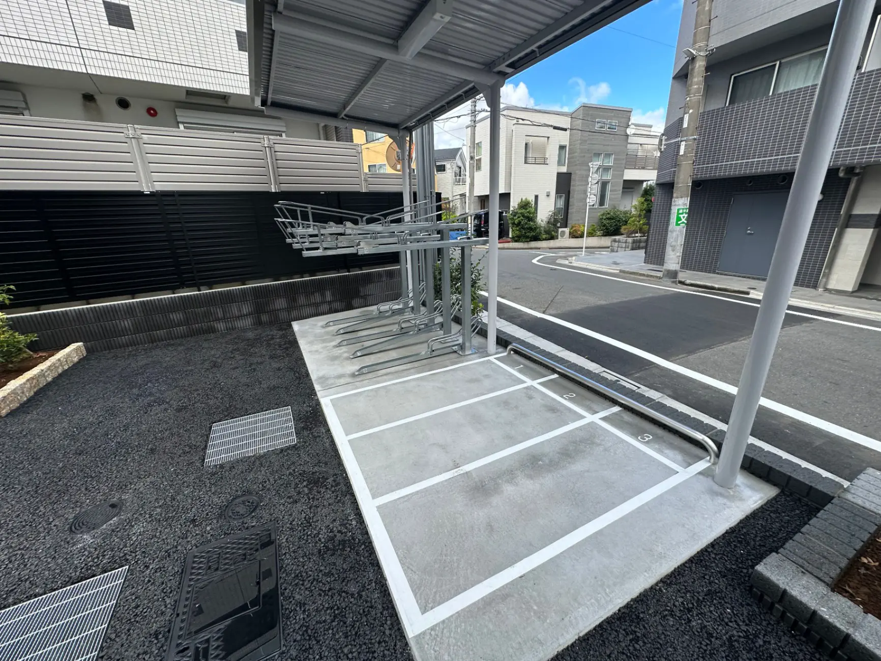 新築の駐輪場、アパートの駐輪スペース、舗装された地面とマークされた自転車スタンド