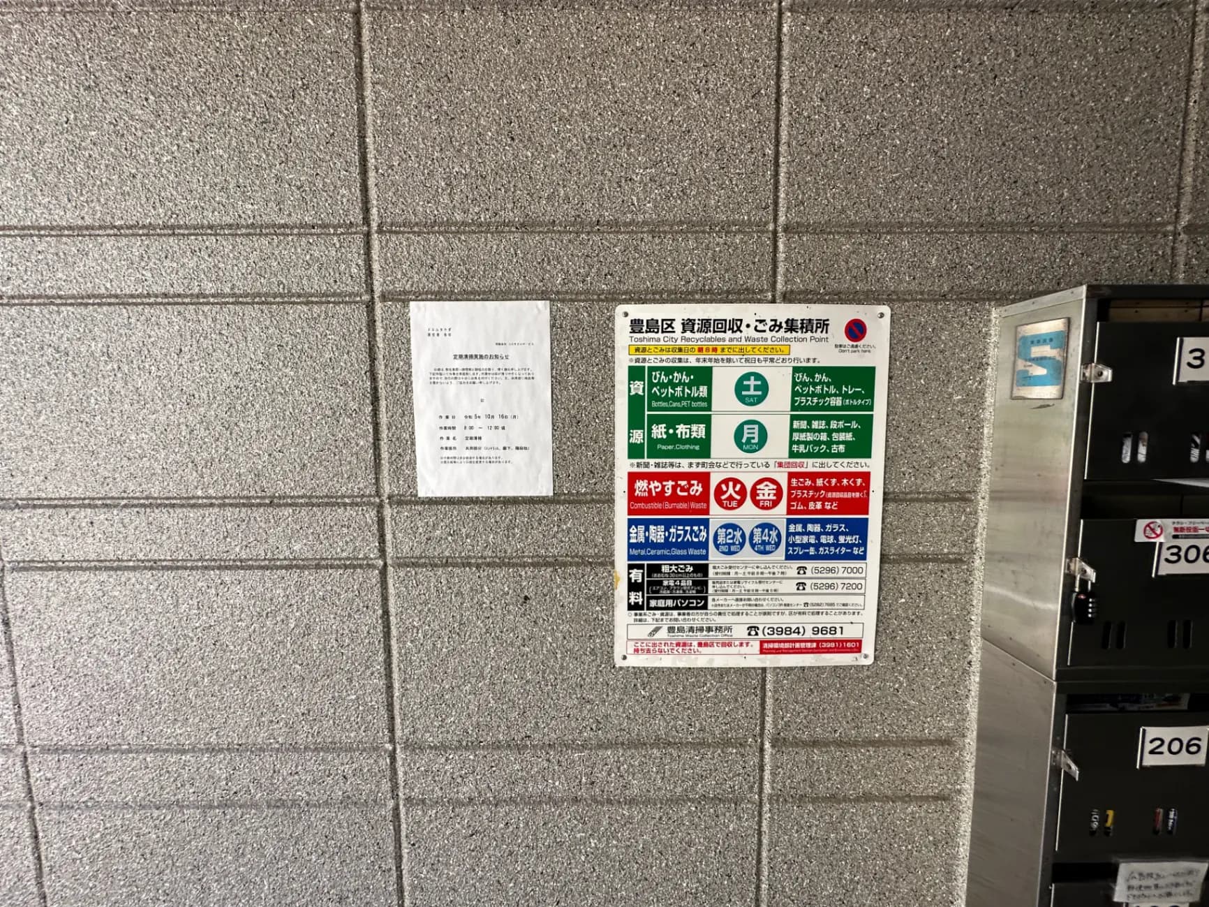 壁に掲示されたゴミ収集日程と分別指示、アパートの郵便受けが写る画像