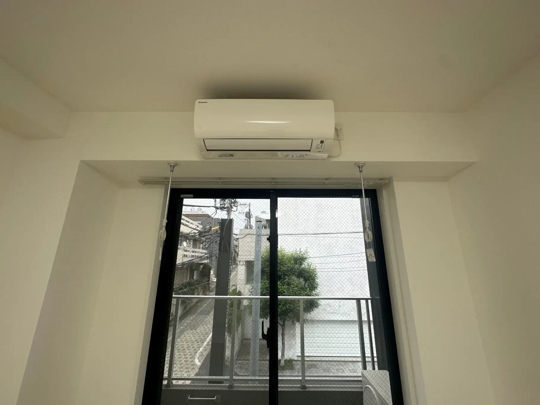 エアコン完備の明るい部屋とベランダが見える窓