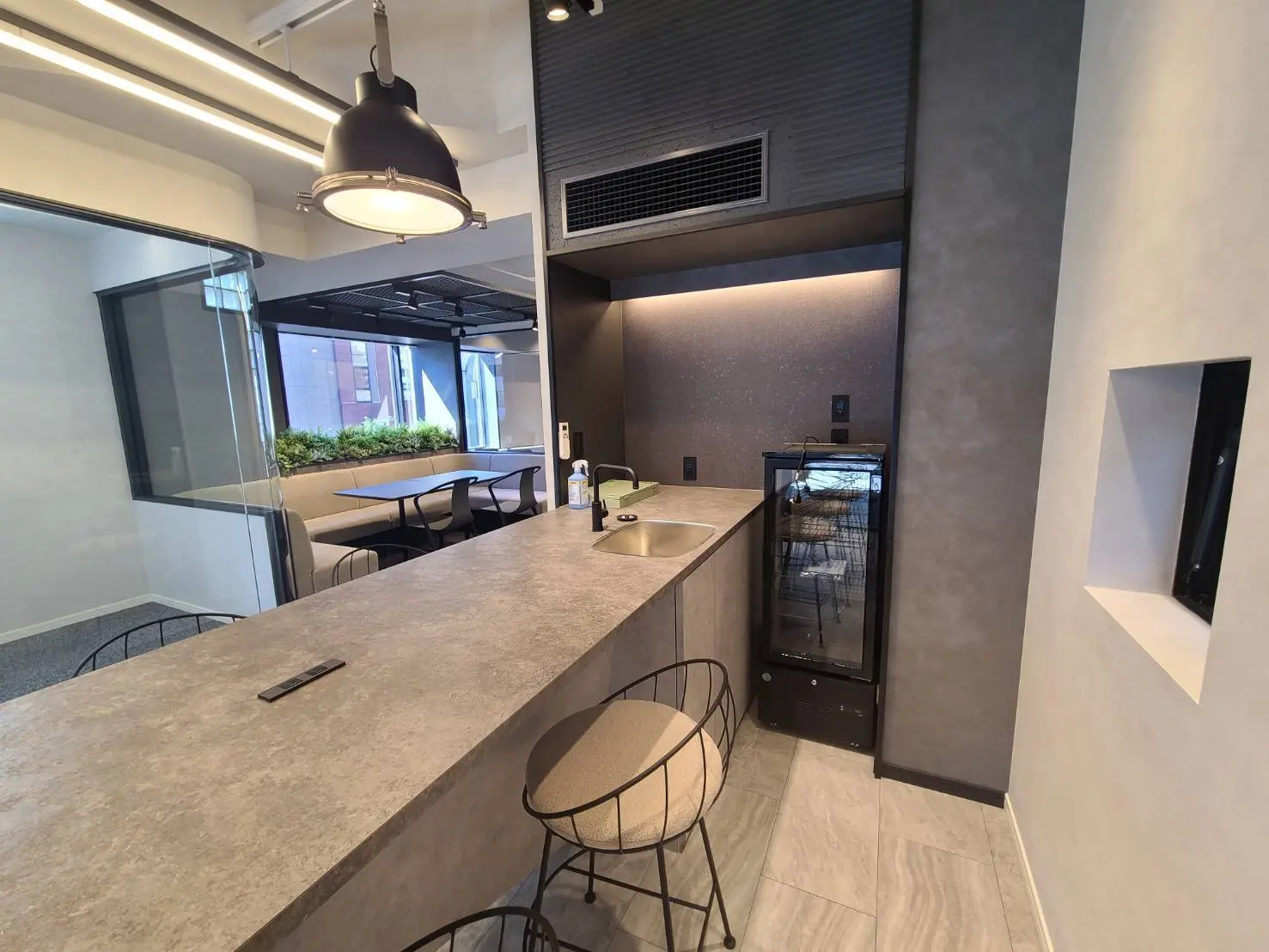 モダンなキッチンカウンターとダイニングエリア、吊り下げ型のライトとクリーンなデザイン