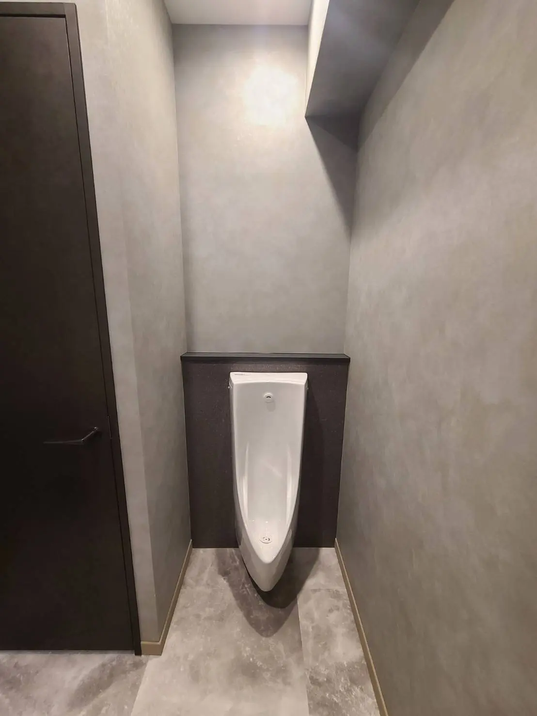 モダンなデザインの公共トイレ内部、清潔な壁と床、暖色系の照明を備えた小便器